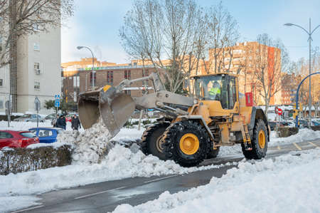 Fuenlabrada, Madrid, Spain; 10-01-2021: Excavator removing the large amount of snow from the road after the storm "Filomena"のeditorial素材