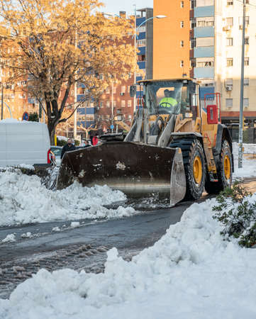Fuenlabrada, Madrid, Spain; 10-01-2021: Excavator removing the large amount of snow from the road after the storm "Filomena"のeditorial素材