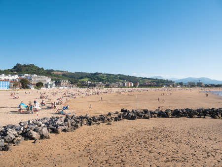 Laredo, Cantabria, Spain; 07 04 2020: View of La Salve de Laredo beach and characteristic rocks as bathers and tourists enjoy a sunny day on vacation with a beautiful blue sky in the backgroundのeditorial素材
