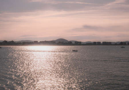 Boats sailing in the Cantabrian Sea at sunset with Salve de Laredo beach in the backgroundの写真素材