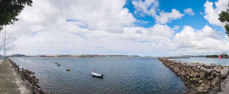 Santander, Cantabria, Spain; 08-16-2021: Panoramic of the bay of Santander with the city in the background, rocks forming a wall and a red sign with the text "forbidden extraction of live bait"のeditorial素材