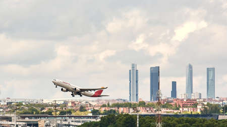 Madrid, Spain; 09-25-2021: Side view of an Airbus A330 aircraft of the Spanish airline Iberia during the take-off maneuve at Madrid Barajas airport with the famous Madrid office towerのeditorial素材