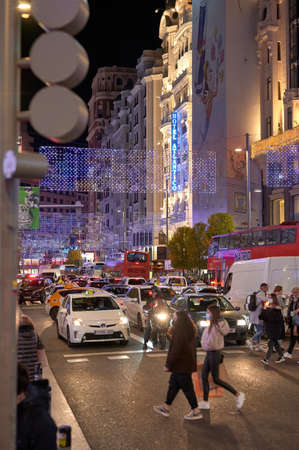 Madrid, Spain; 02-12-2021: People crossing a traffic light on Gran Via street in Madrid with Christmas decorationsのeditorial素材