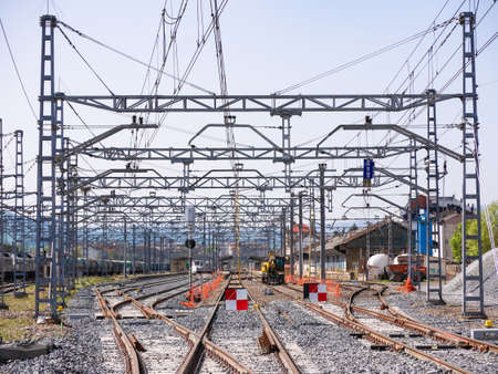 Monforte de Lemos, Lugo, Spain; 04-30-2022: Train tracks under construction with red and white signs preventing traffic and a safety pole connecting the catenary to the ground and an excavator machineのeditorial素材