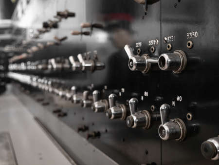 Macro view of the gray knobs and switches of the switch motors of an old interlock (control area) of a railway train station on a black backgroundの写真素材