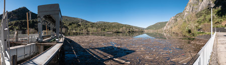 Panoramic of the arrival of the Sil River to the Penarrubia reservoir, dragging tons of trees, vegetation remains and garbage in its course until they pile up in the damの写真素材