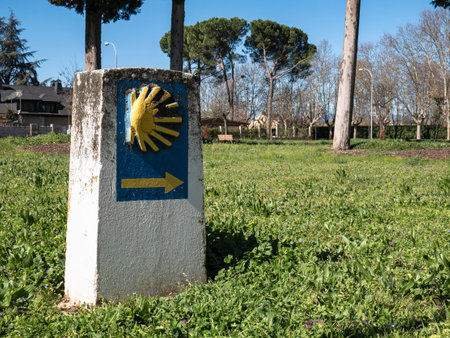 Stone monolith, quite deteriorated, located in a green grass park indicating the direction to follow for pilgrims of the Camino de Santiago on their long journey to reach Santiagoの写真素材