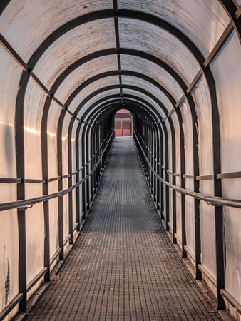 Pedestrian tunnel on an upward slope composed of a longitudinal arched metal structure of the same material and covered with a layer of translucent plasticの写真素材