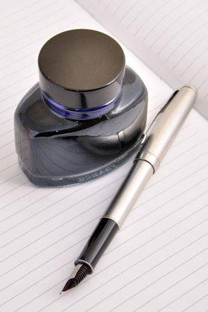 Fountain pen and ink bottle lying on a clean sheet of notebook
