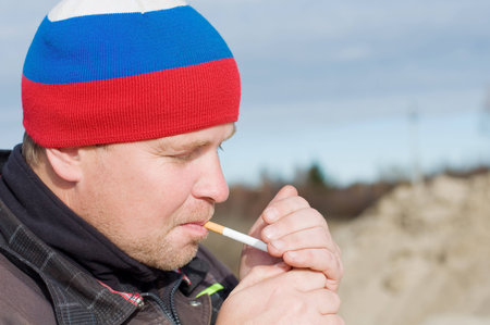 Male construction worker smokes a cigarette outdoorsの写真素材