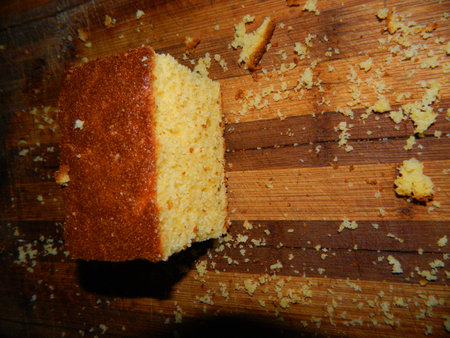 On a wooden board is a big piece of the cake of yellow cornmeal