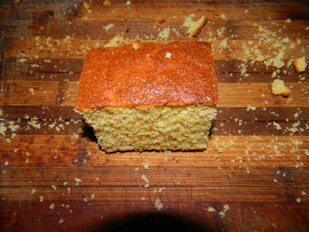 On a wooden board is a big piece of the cake of yellow cornmeal
