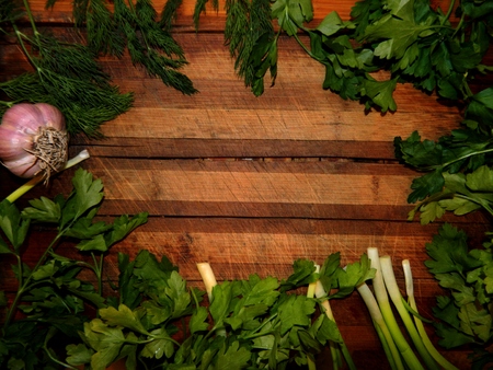 wooden board decorated frame of garlic, parsley, dill and fresh green onions, bright healthyの写真素材