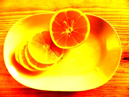 on light wood chopping board is a white oblong dish with chopped fresh lemon rings with stones on a horizontal surface top viewの写真素材