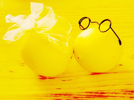 on light wood chopping board are a pair of lovers kissing and yellow lemons boy in dark glasses and a girl with a white bow on a horizontal surface with top view and frontの写真素材