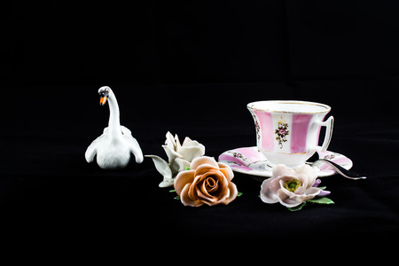 An antique porcelain composition made by three roses, a swan and a coffe cup with ornamentsの写真素材