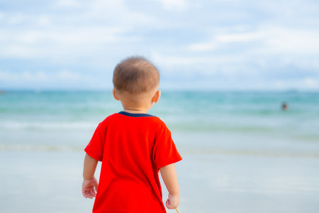 The baby walked over the beach and looked out at the sea.の写真素材