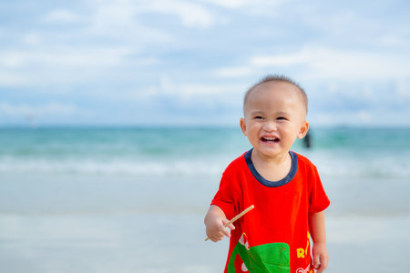 The toddler smiled happily to come to the sea. With family on vacation.の写真素材