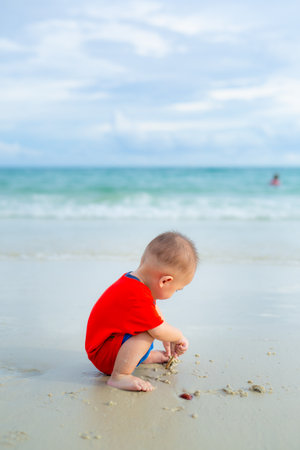 Babies explore and play in the sand alone by the sea.の写真素材