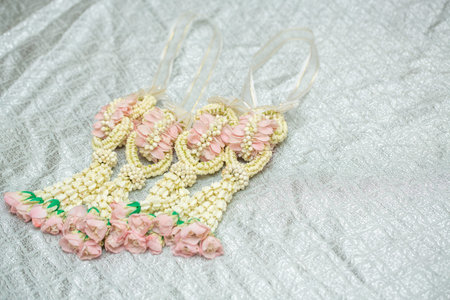 Beautiful Thai-style jasmine garland on a silver cloth background with an ancient Thai pattern.