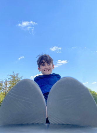 Kid feet in a park. Boy having fun playing in nature. Blue sky. Copy space. Child smiling and laughingの写真素材