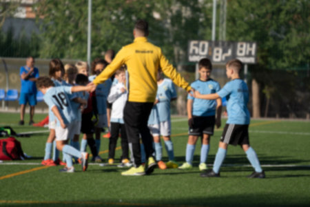 Coach hand in hand with kids showing closeness and motivating players. Kids football coaching...