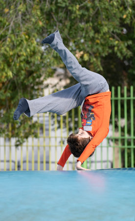 Kid making somersault somersault outdoor in inflatable air cushion jumping bouncer playground