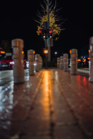 traffic barrier posts bollards and pedestrian path illuminated by cars headlight and traffic lightsの写真素材