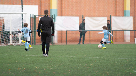 Kids football match. Soccer player run to shoot ball to goal. Concept of making goalsの写真素材