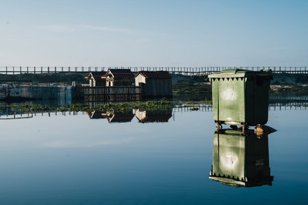 Green bin and houses over water. Flooding in Espinho , Portugal. 9 January 2023