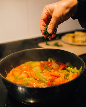 Chef hand adding parsley to a vegetable stir fry. Healhy food cooking concept