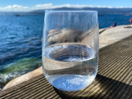 Cold glass of water by the sea on a hot summer dayの写真素材