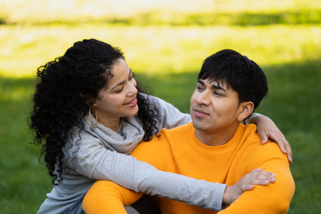 Young couple in a relaxed time in a park. Girlfriend hugging and looking at her boyfriendの写真素材