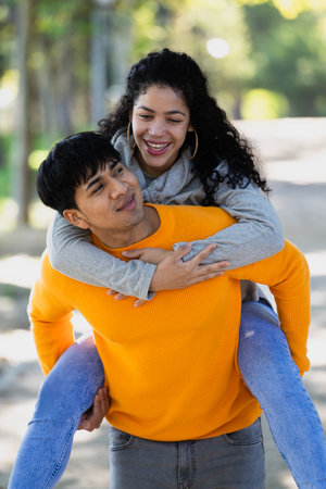 rtrait of smiling young couple having fun.Man piggybacking woman in a public park in Madrid.の写真素材