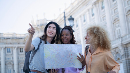 Group of multi ethnic young travellers looking looking and pointing somewhere to visit. A woman is...