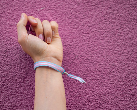 Close-up of closed fist with transgender bracelet over violet pink background. Copy space.の写真素材