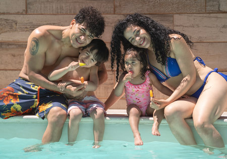 Cheerful dominican family of four enjoying summer holidays in a pool