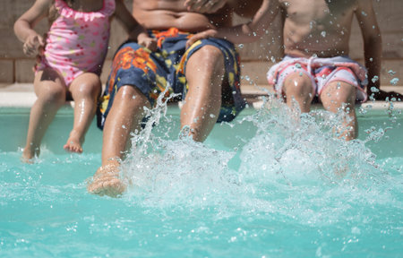 Unrecognizable family splashing water at the edge of the pool. Summer holidays concept.の写真素材
