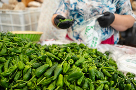 Gaician woman is selling green padron peppers selling at a fish market in Spain.