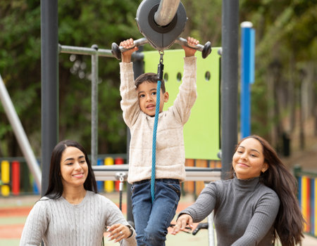 LGBTQ lesbian family enjoying with their son in a zip line outdoors in a park.の写真素材