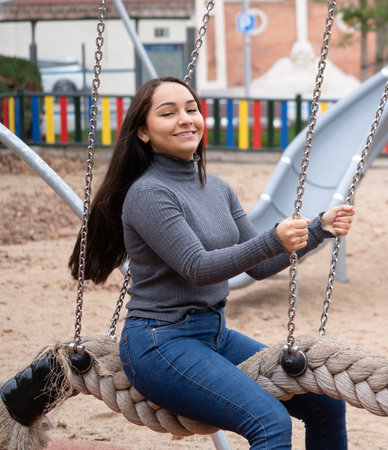 Young smiling woman having fun in a swing in a park.の写真素材