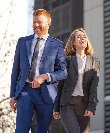 Business man and a woman happy and committed for their goals, walking outside their office.の写真素材