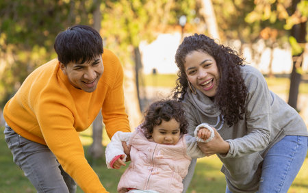Close up front view of happy hispanic family of three enjoying time outdoors together.の写真素材
