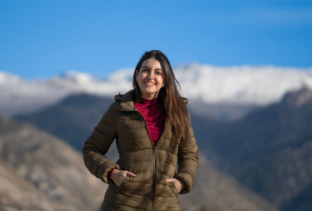 Portrait of a smiling woman enjoying a sunny winter day in a mountain landscapeの写真素材