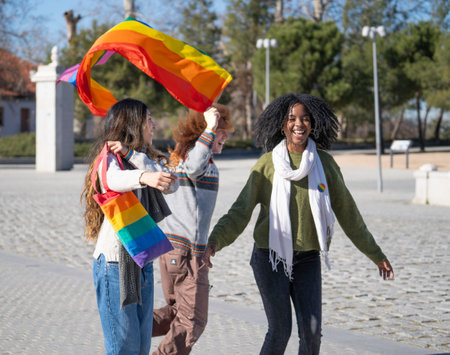 Multiracial group of friends celebrating gay pride holding rainbow flag and smilingの写真素材