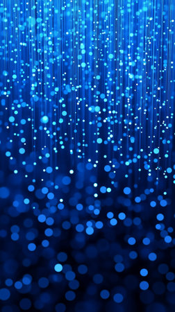 Sparkling blue bokeh lights falling against a dark background create a festive and magical...