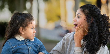 Portrait of surprised latin mother talking with his unimpressed son outdoors.