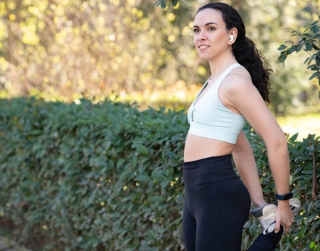 Young athlete warming up her legs before a workout session outdoors