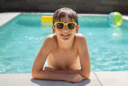 Portrait of smiling young boy with relaxing sunglasses at the pool's edgeの写真素材