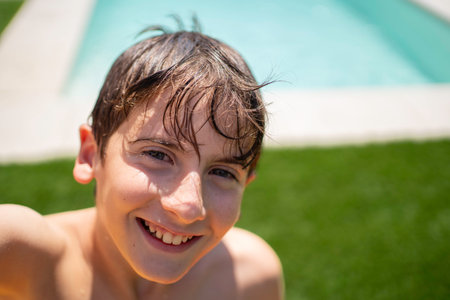 Portrait of smiling boy with wet hair by the poolside enjoying summer vacation with copy spaceの写真素材